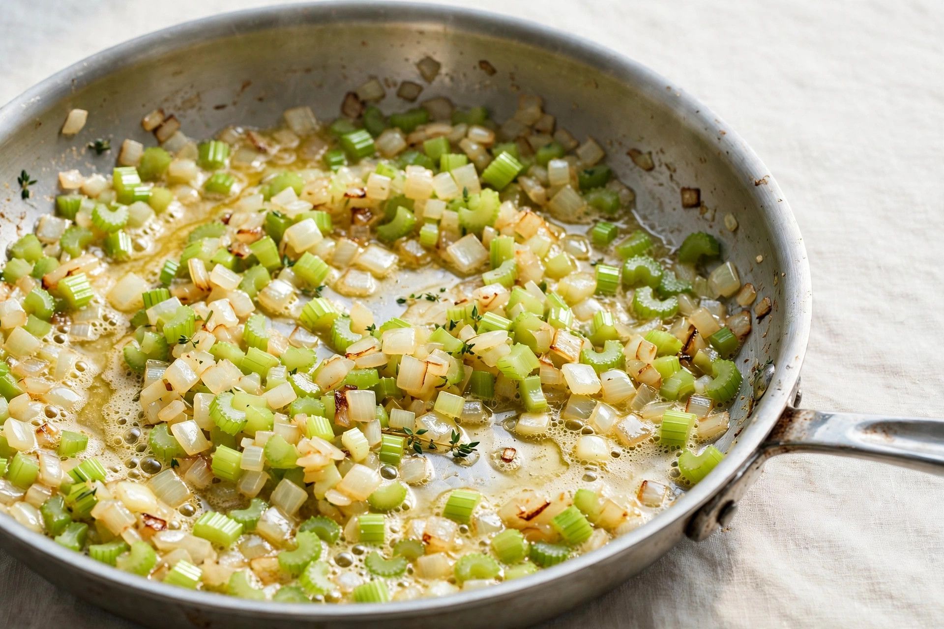 Diced celery and onion sauteing in melted butter with sage in a large skillet