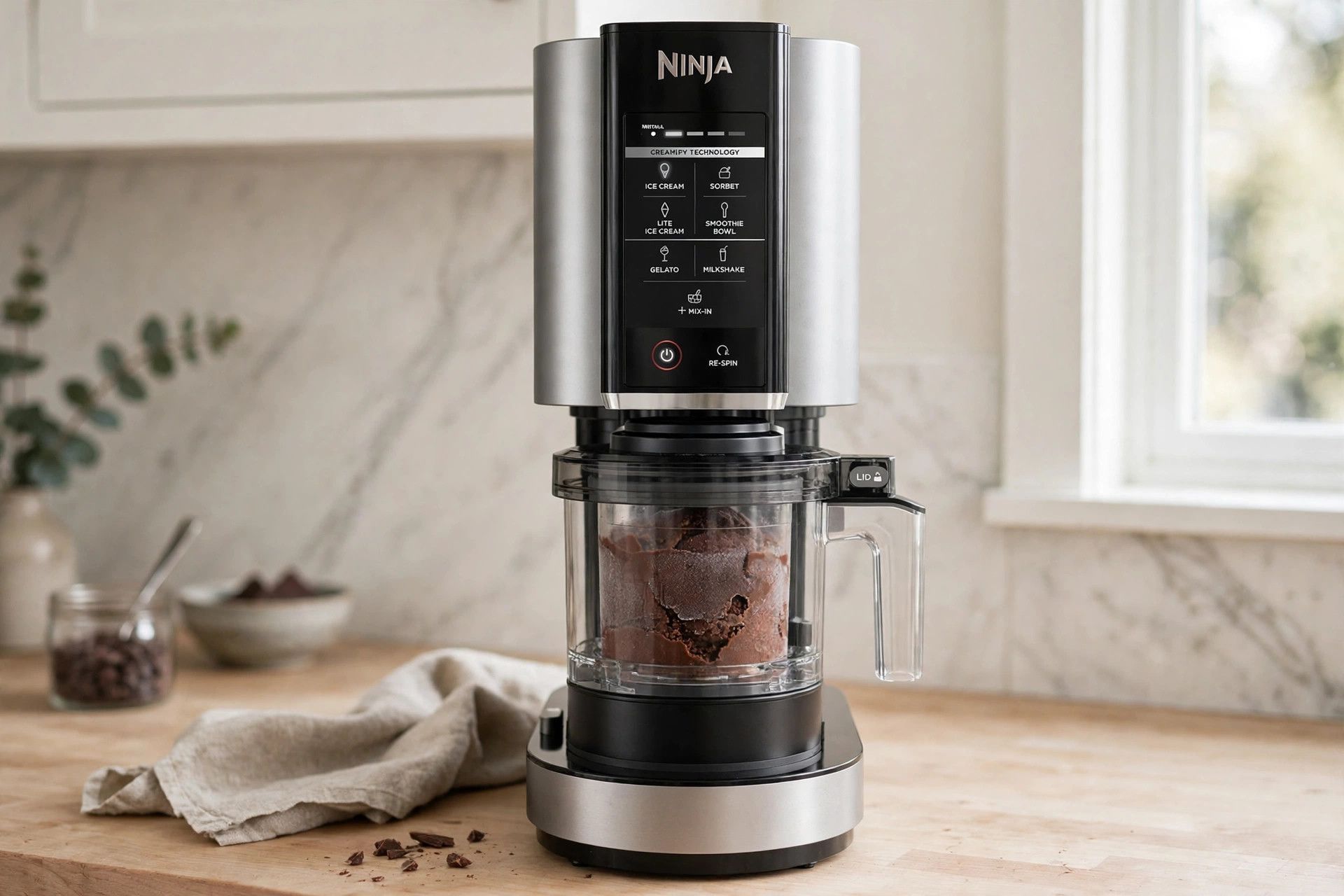 The frozen chocolate fudge pint loaded into a countertop Ninja Creami machine, ready to spin