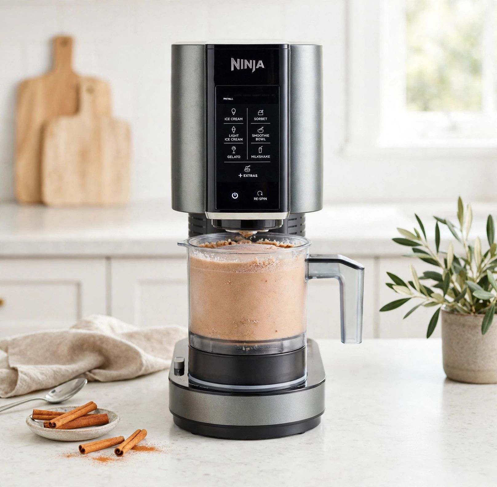 The frozen cinnamon roll pint loaded into a countertop Ninja Creami machine, ready to spin