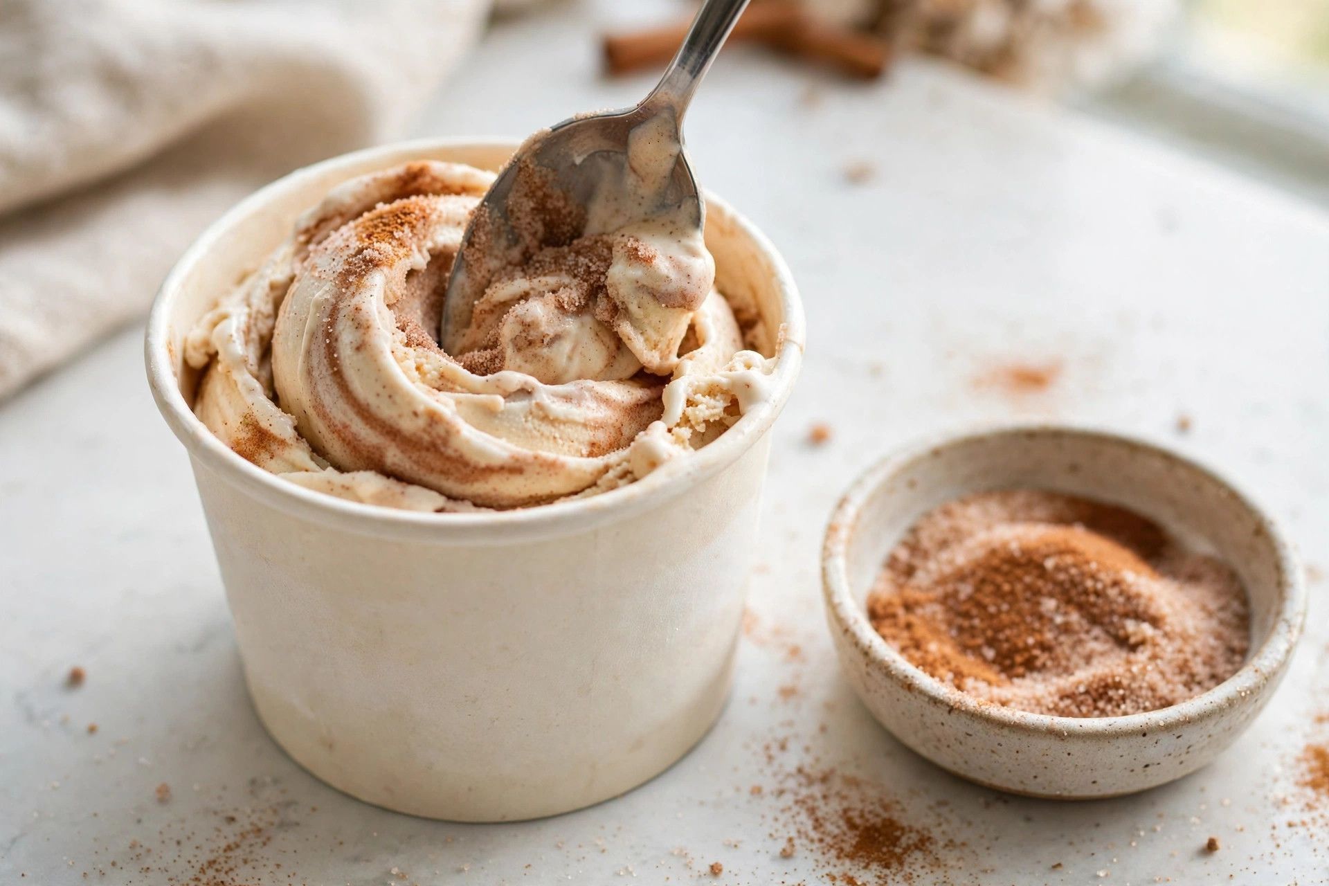 Swirling cinnamon sugar through freshly spun cinnamon protein ice cream with a spoon, showing the ribbon